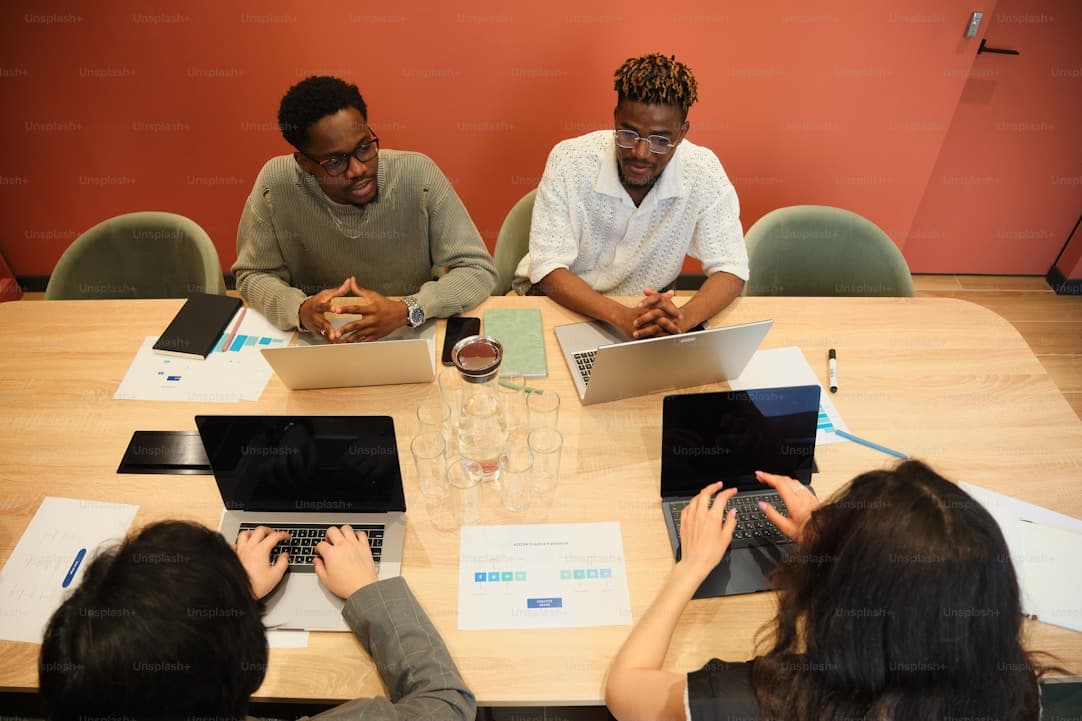 Four people working together on laptops around a table.